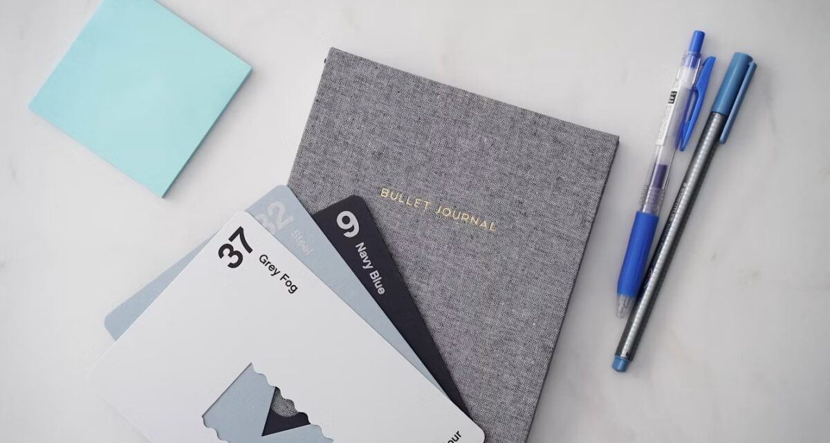 Notebook and pens on a desk, representing a simple message tracker